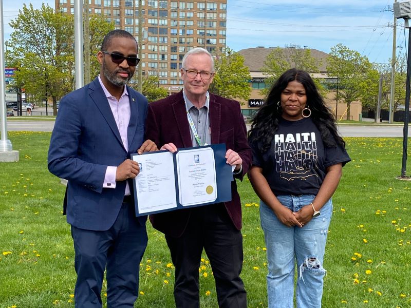 Chair Henry presenting a proclamation certificate for Haitian Flag Day